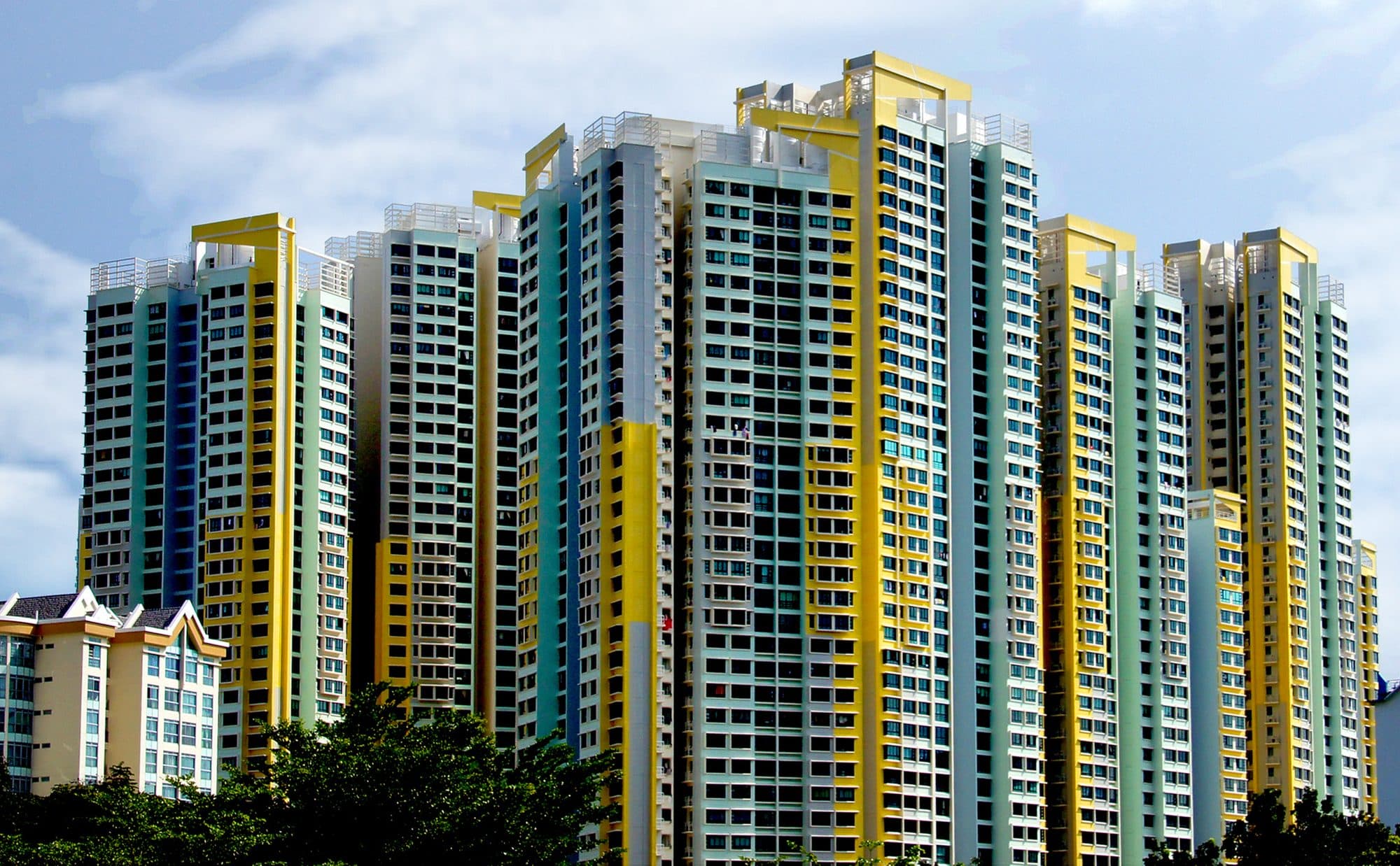 High-rise HDB apartment blocks in Singapore, painted in pale yellow, green and white