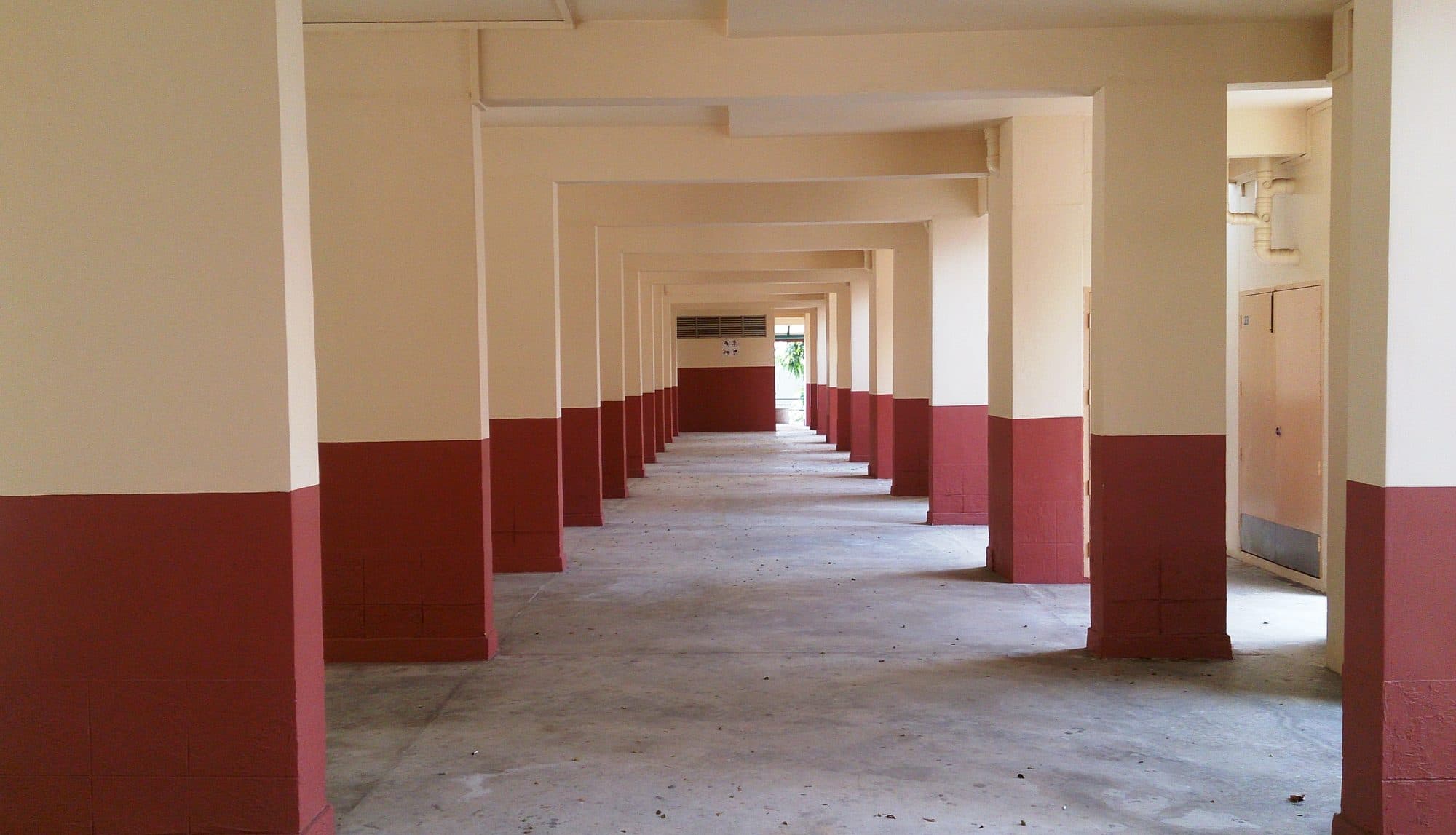 The open void deck running beneath a block of HDB flats in Singapore, columns receding into the distance